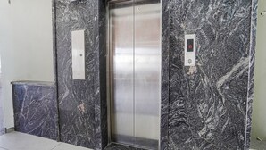 An elevator with a marble wall, a control panel, and a trash bin. - FabHotel Prime Jashan Paradise - MP Nagar (Bhopal)