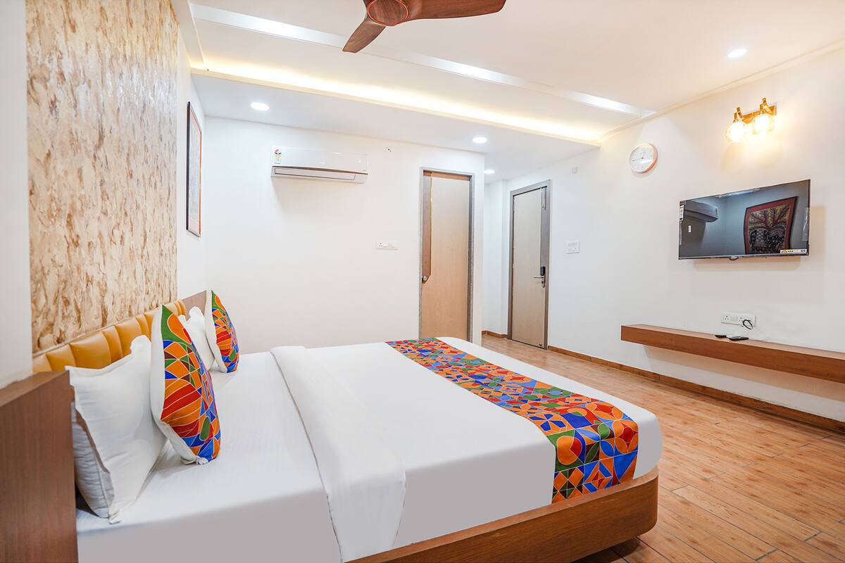 A modern hotel room with a large bed, a TV mounted on the wall, and a ceiling fan.