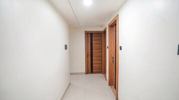 Un corridoio con pareti bianche, pavimento piastrellato e porte in legno.