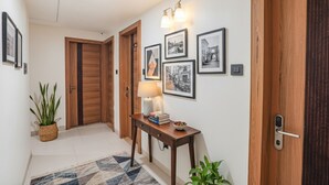 Un couloir avec des portes en bois, une lampe fixée au mur et des tableaux encadrés.