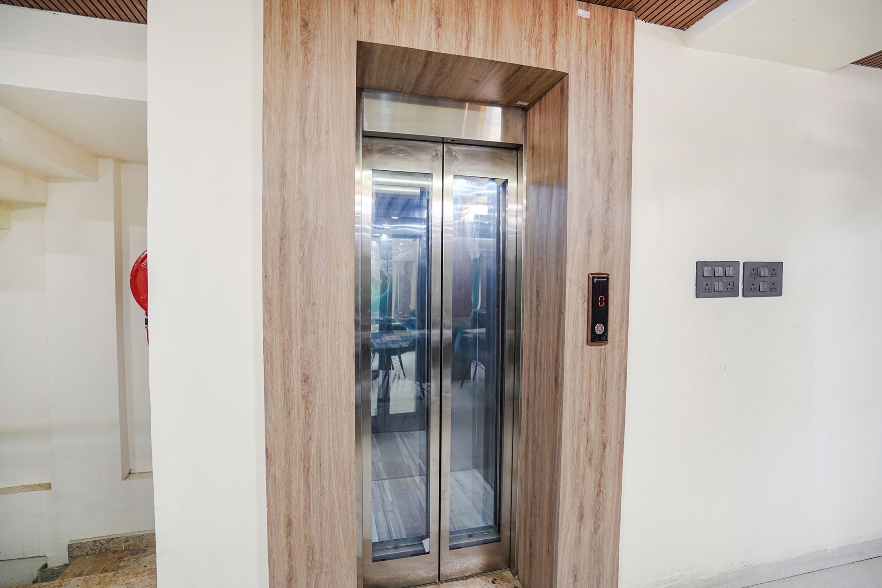 Un ascenseur doté de panneaux en bois, d’un panneau de commande numérique et d’un panneau de signalisation indiquant clairement la sortie de secours.