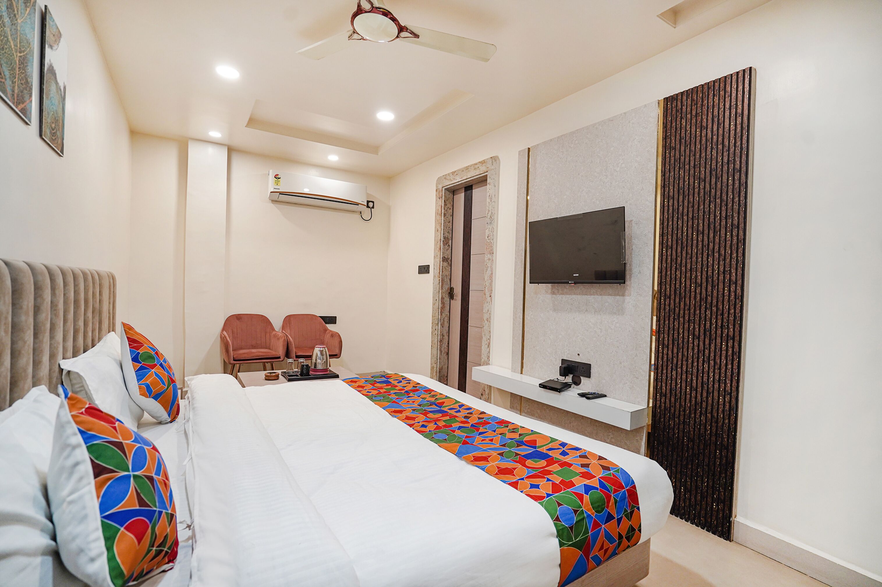 A hotel room with a bed, a TV, a desk, and a seating area.