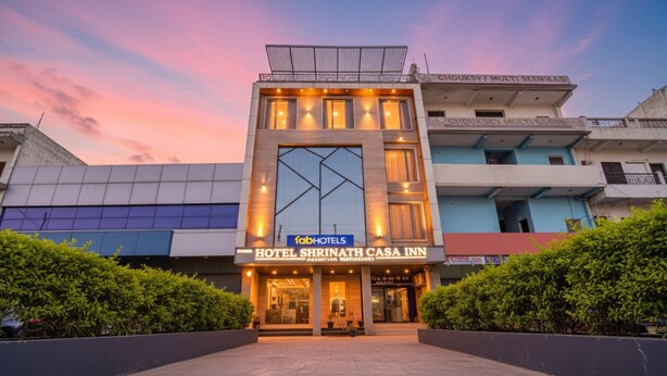 Un hôtel moderne doté d’une entrée imposante, d’une grande façade vitrée et d’une terrasse sur le toit.