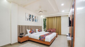 Une chambre d’hôtel moderne avec un grand lit, une table de chevet, un bureau, une chaise, une télévision et une plante.