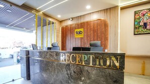 Un comptoir d’accueil avec un plateau en marbre et un mur recouvert de panneaux en bois derrière.