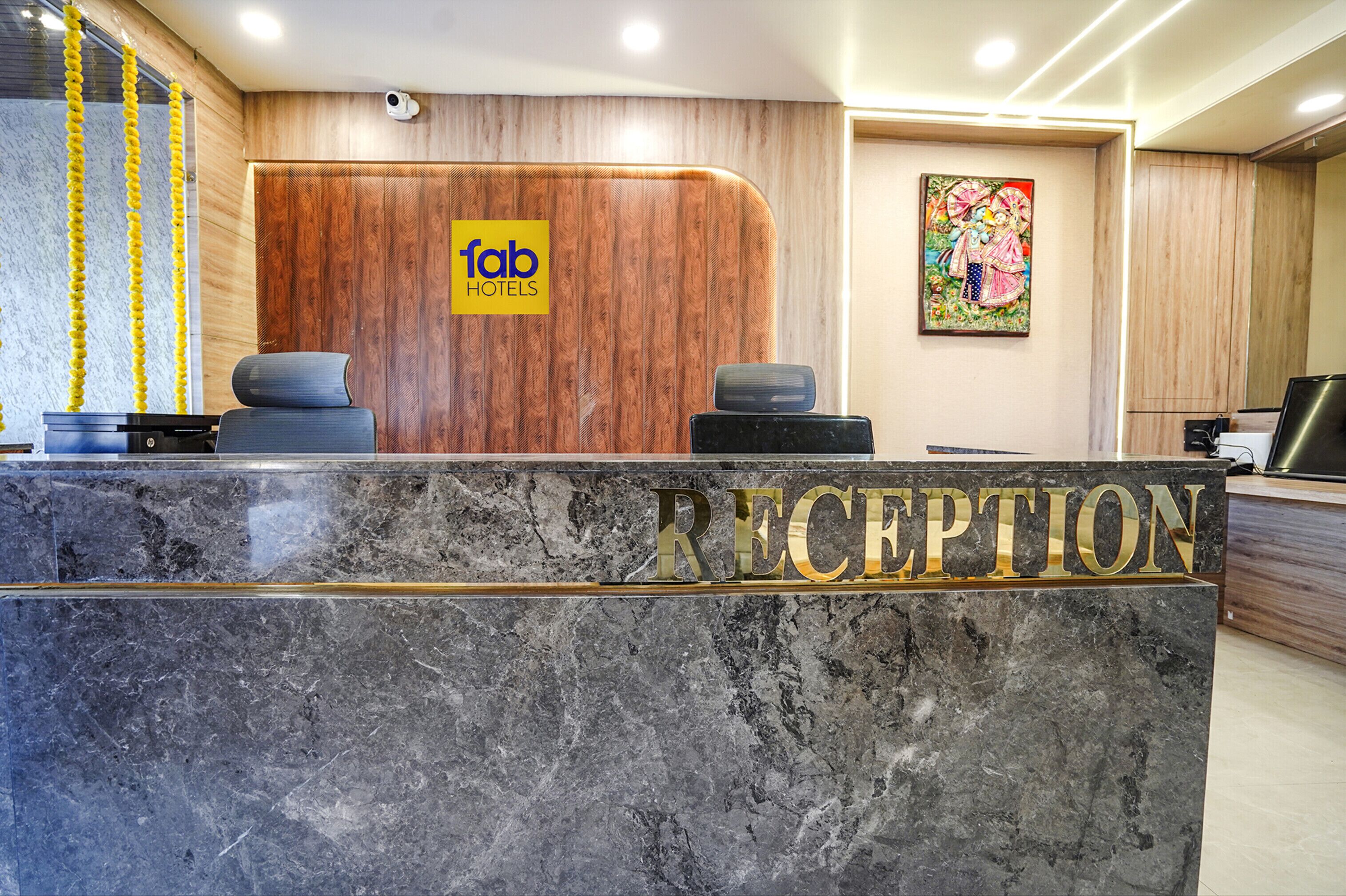 Un espace d’accueil d’hôtel avec un comptoir en marbre, un mur revêtu de panneaux en bois et un bureau de réception.