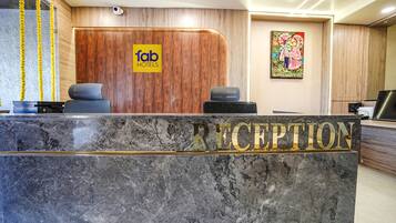 Zona de recepción de un hotel con un mostrador de mármol, un panel de pared de madera y un escritorio para la recepción.