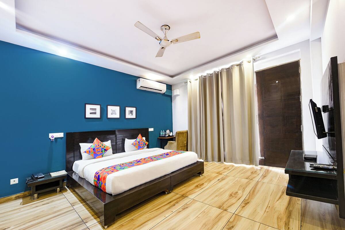 Une chambre d’hôtel moderne équipée d’un grand lit, d’un ventilateur de plafond, d’une télévision et d’un mini-bar.