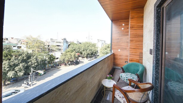 A balcony with a view of a cityscape, a small table with a potted plant, and two chairs. - Fabhotel Vibe (Noida)