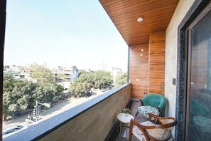 En balkon med udsigt over bybilledet, et lille bord med en potteplante og to stole.