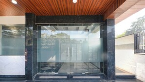 A modern entrance with glass doors, a wooden ceiling, and a tiled floor. - Fabhotel Vibe (Noida)