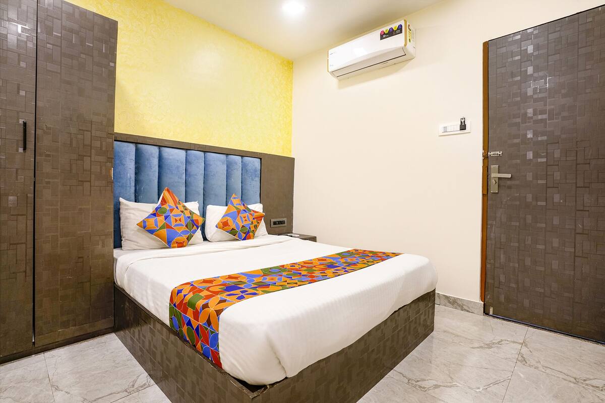 Habitación de hotel con cama, cabecero, aire acondicionado de pared y una puerta.