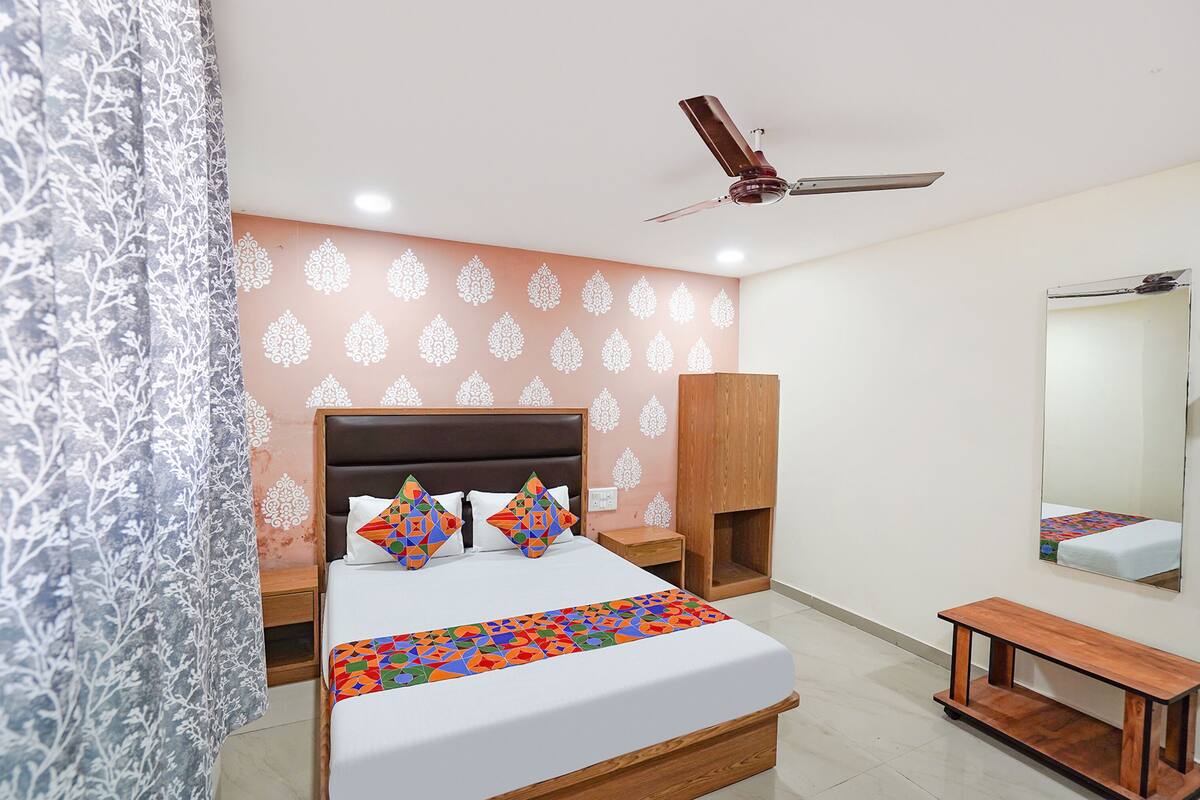 A bedroom with a bed, bedside tables, a ceiling fan, a mirror, and a bench.