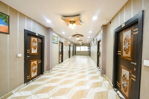 Ein Hotelkorridor mit gemusterten Bodenfliesen, dekorativen Türen und Deckenleuchten.