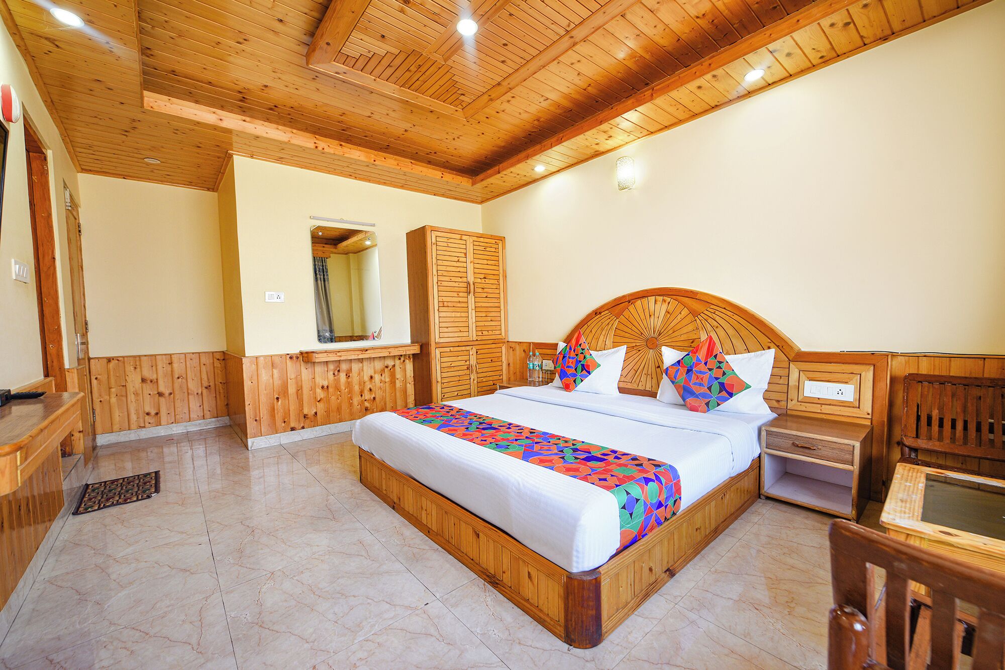 A wooden-paneled bedroom with a bed, a nightstand, a mirror, and a wooden bench.
