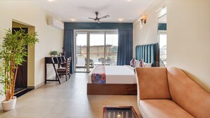 A hotel room with a bed, a sofa, a dining table with chairs, a potted plant, and a view of the outside. - FabHotel Jingle Tree Resort Nr Arambol Beach (Arambol)