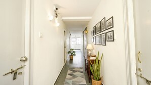 Un couloir décoré d’un tapis à motifs, de plantes en pot et de tableaux encadrés accrochés au mur.