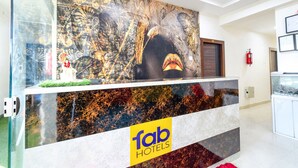 Un comptoir d’accueil orné du logo « fab hotels », une cloison en verre et un extincteur fixé au mur.