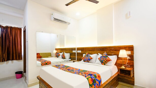 Une chambre d’hôtel avec un grand lit, une tête de lit en bois, une table de chevet avec une lampe, un miroir et un appareil de climatisation.