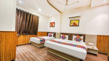 A hotel room with two beds, wooden paneling, a ceiling fan, an air conditioning unit, and two wall-mounted paintings.