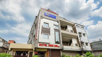 A hotel with a modern facade, balconies, and a sign for 'HOTEL SHRI SAID'.