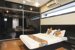 A modern hotel room with a large bed, a mirror, and an air conditioning unit. - Fabexpress Star Light (Pune)