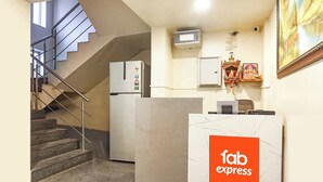 Een hotellobby met een receptiebalie met de tekst 'fab express', een trap, een koelkast en een beveiligingscamera.