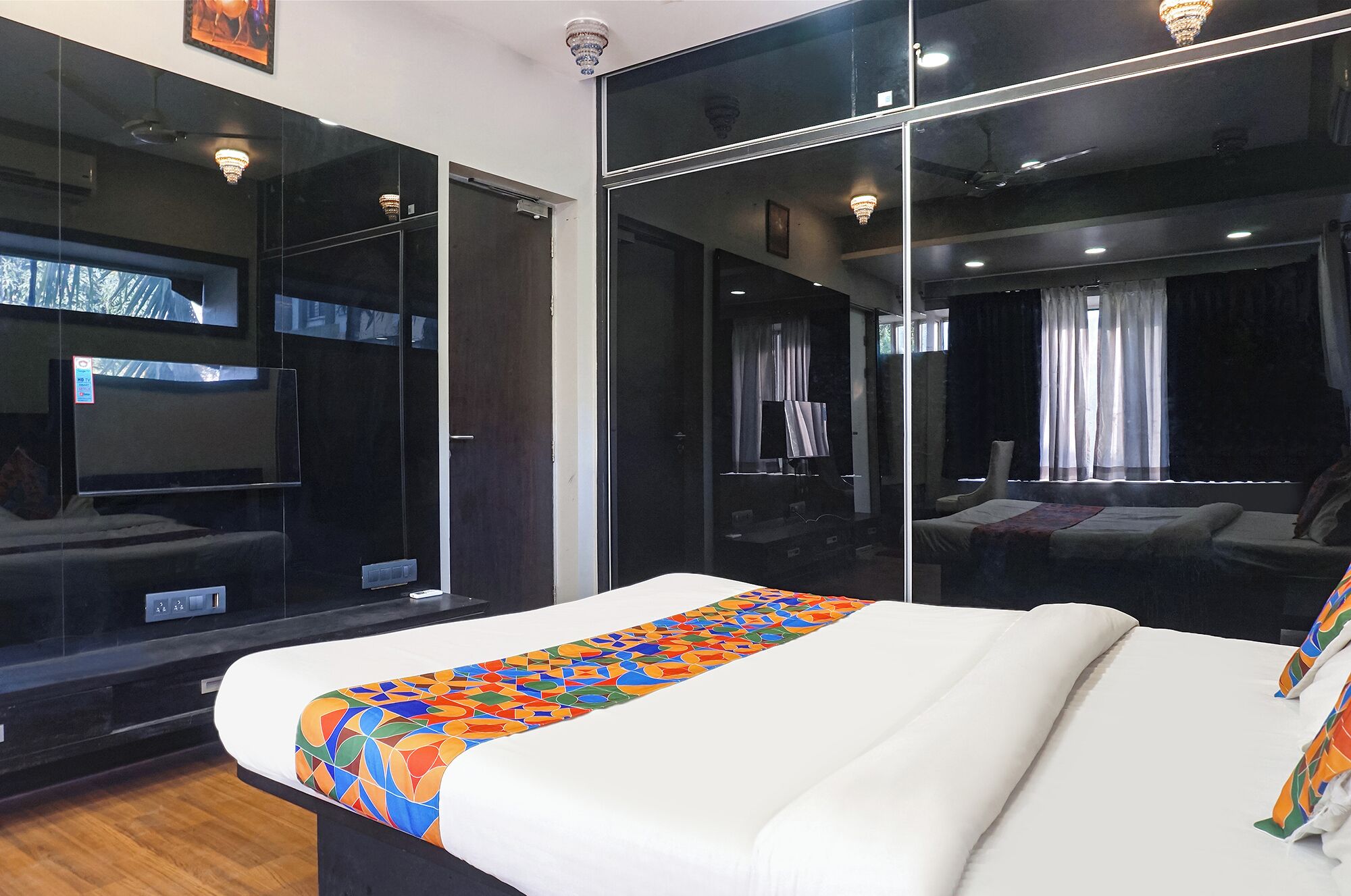 A modern hotel room with a large bed, a mirror, and a view of the city.