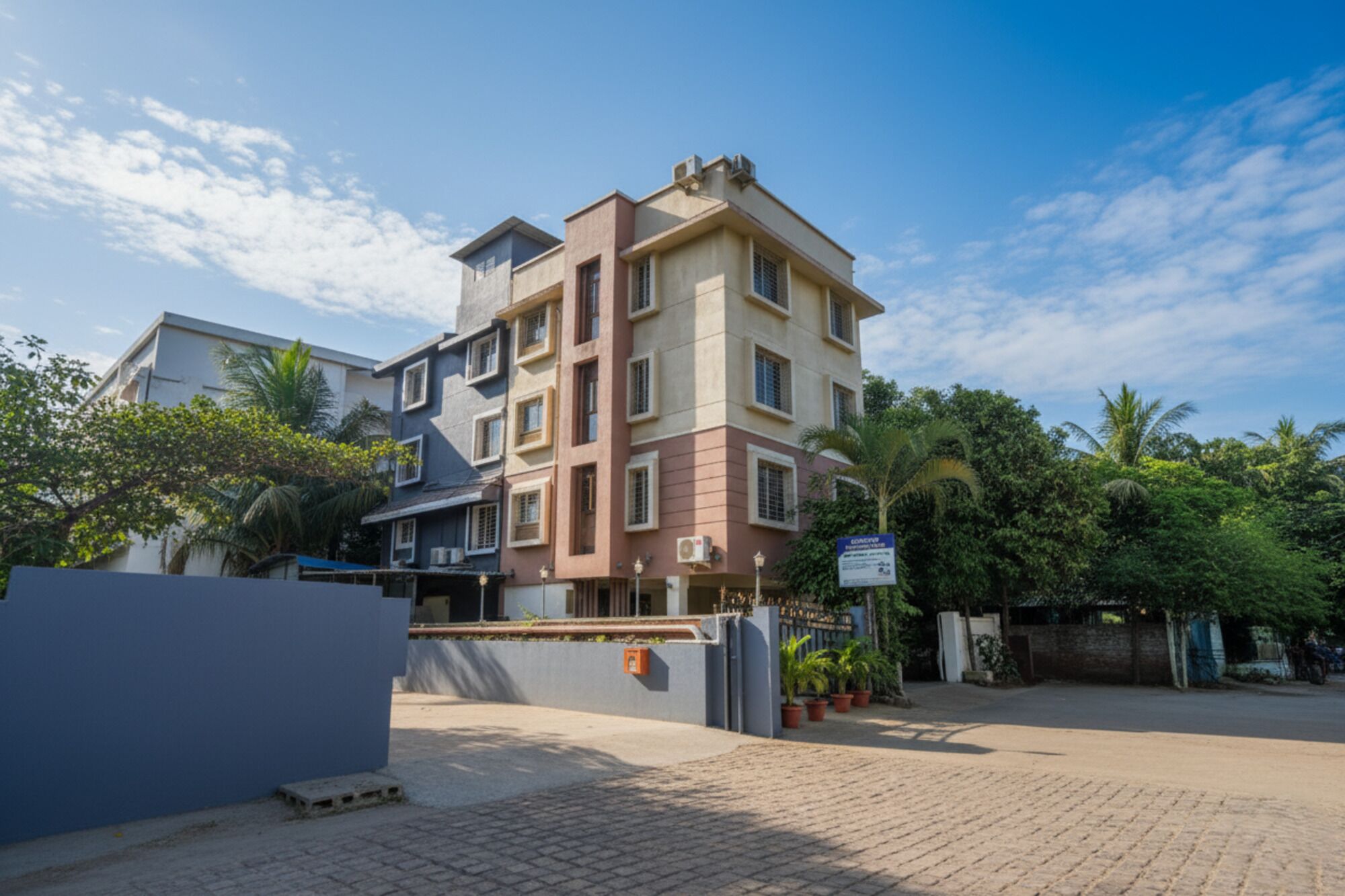 A multi-story residential building with a flat roof, a gated entrance, and a paved driveway.