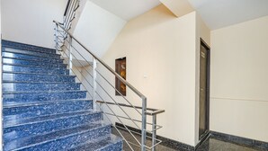 Eine Treppe mit blauen Marmorstufen und einem Metallgeländer, die zu einer Tür mit einer Holzvertäfelung führt.