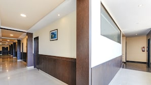 Ein moderner Hotelgang mit poliertem Boden, Holzvertäfelung, einem gerahmten Bild an der Wand und einem Feuerlöscher.