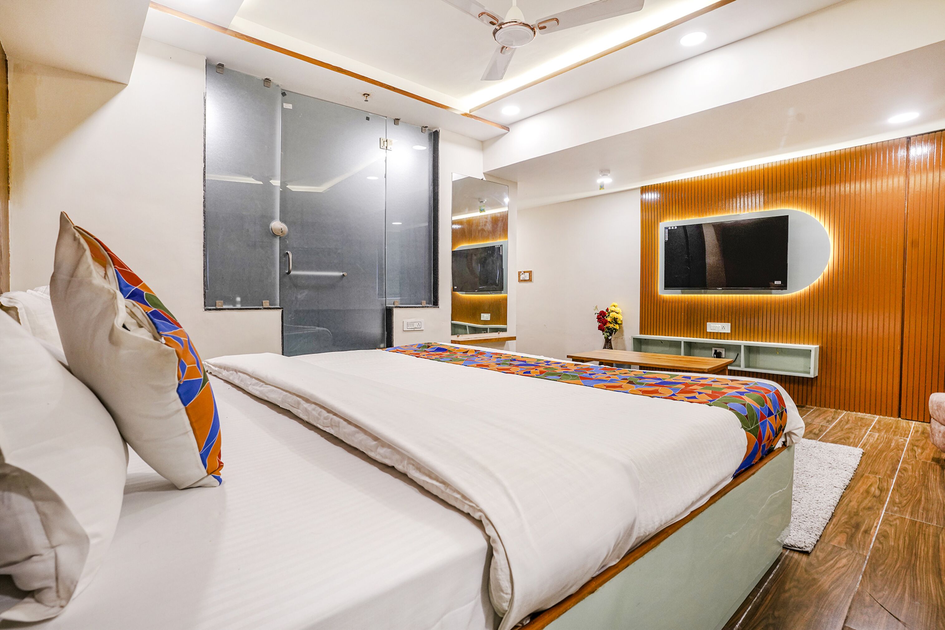 Ein modernes Schlafzimmer mit einem großen Bett, einem an der Wand montierten Fernseher und einer Wandverkleidung aus Holz.