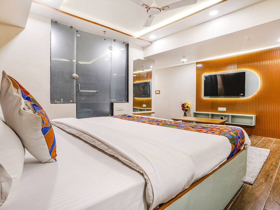 Ein modernes Schlafzimmer mit einem großen Bett, einem an der Wand montierten Fernseher und einer Wandverkleidung aus Holz.