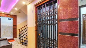 Ein Hotelzugang mit einem Metallgitter, Marmorboden und einer Treppe mit Geländer.