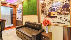 Eine Lobby mit Ledersofa, grüner Wand und einem Plakat der Straßenbahn.