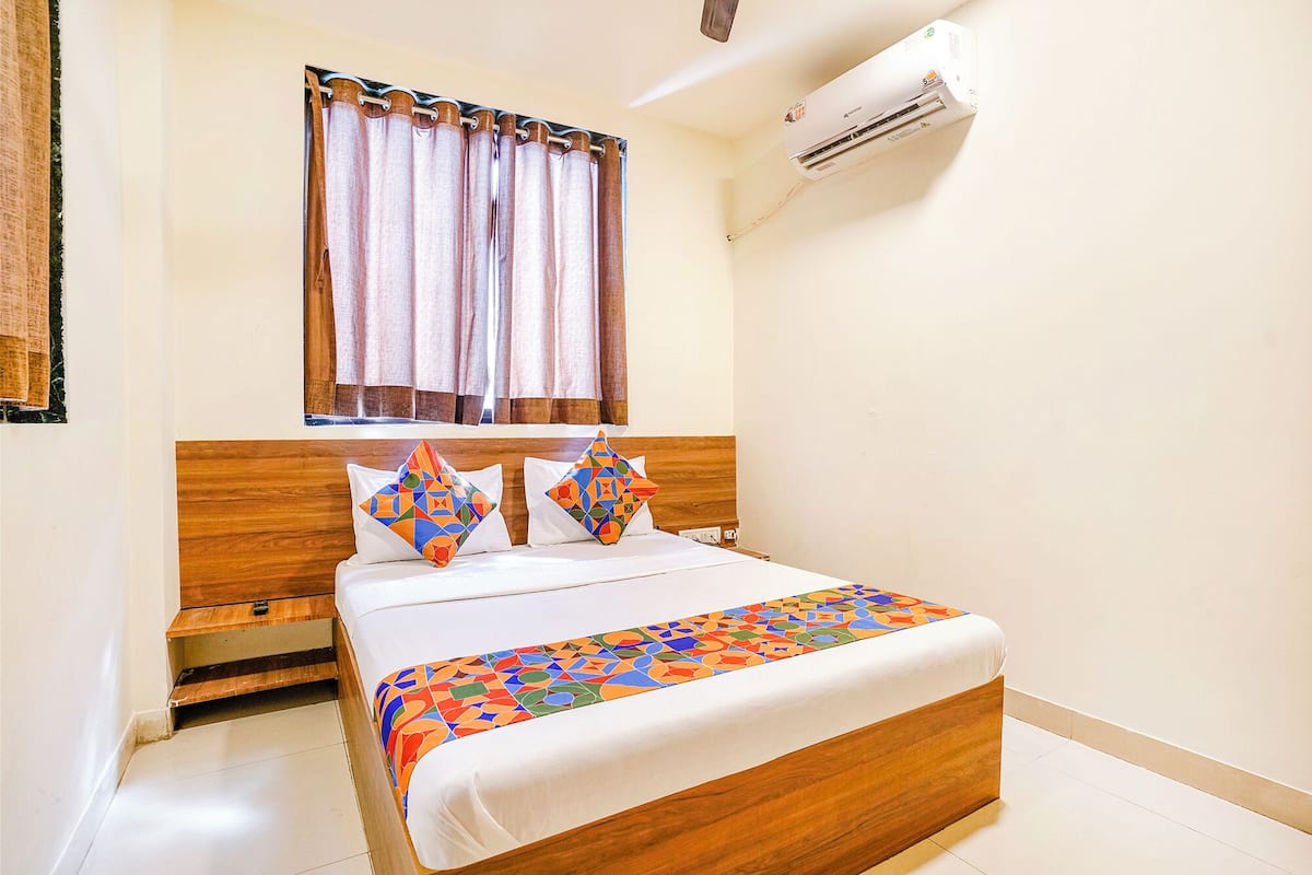 Une chambre à coucher avec un lit en bois, une fenêtre avec des rideaux et un appareil de climatisation.
