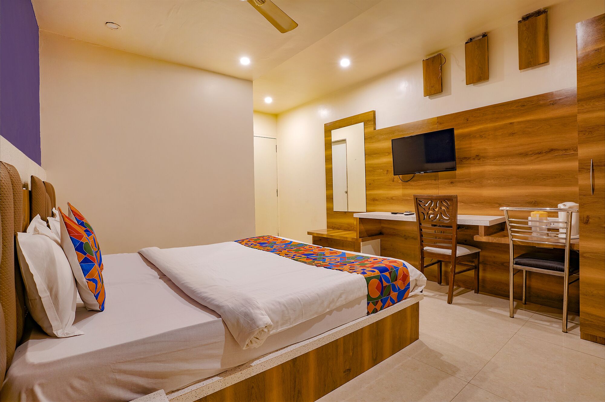 A bedroom with a bed, a desk, a chair, and a TV.