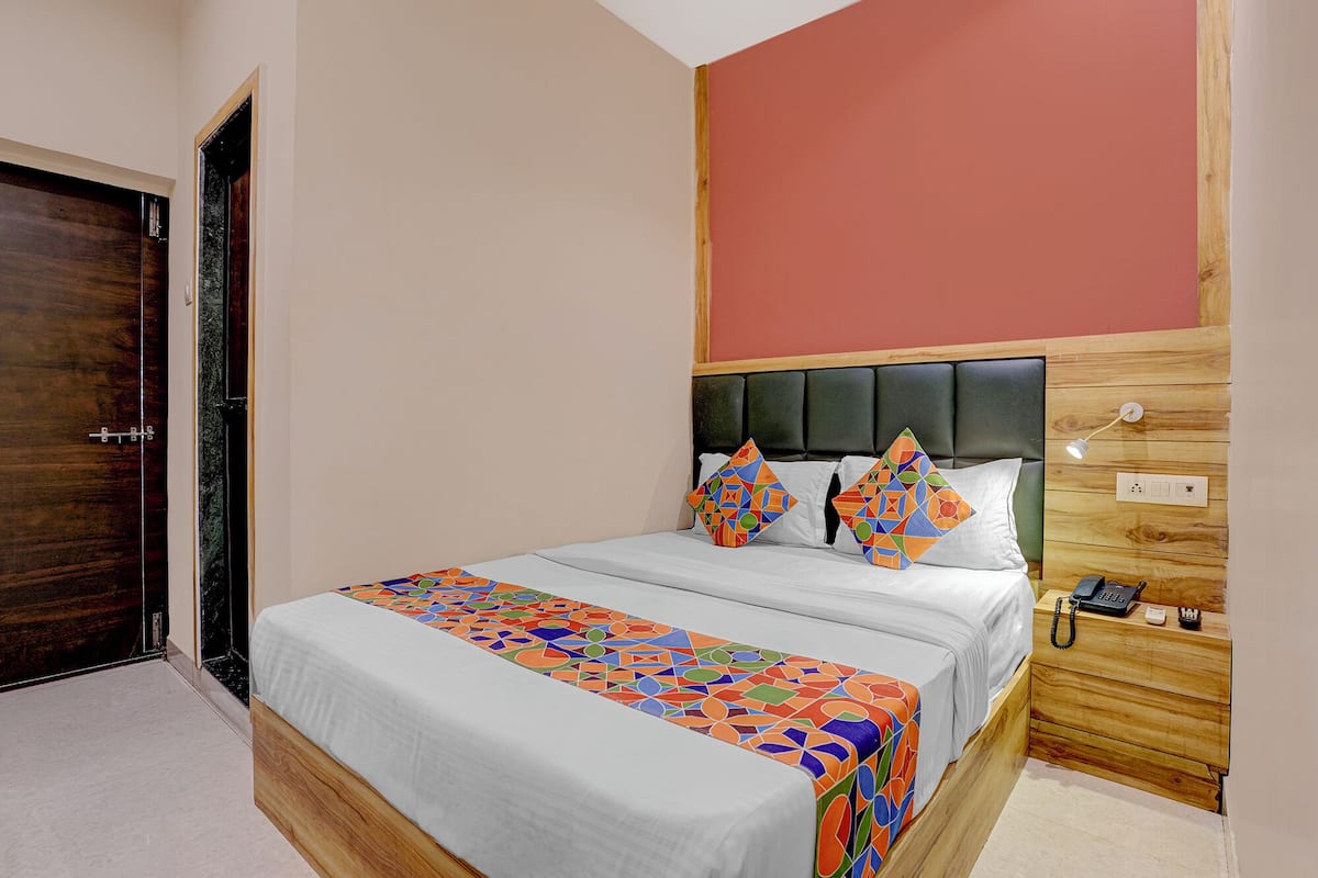 Un dormitorio con cama, almohadas, una mesita de noche con teléfono y cabecera de madera.