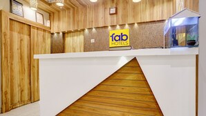 Ein Empfangsschalter mit Holzoptik, ein 'fab hotels' Schild und eine Uhr an der Wand.