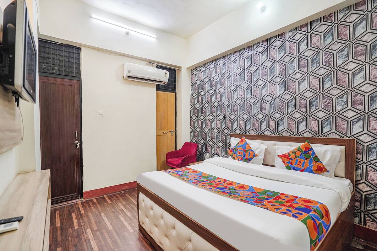 A bedroom with a bed, a red chair, a wooden door, and a patterned wall.