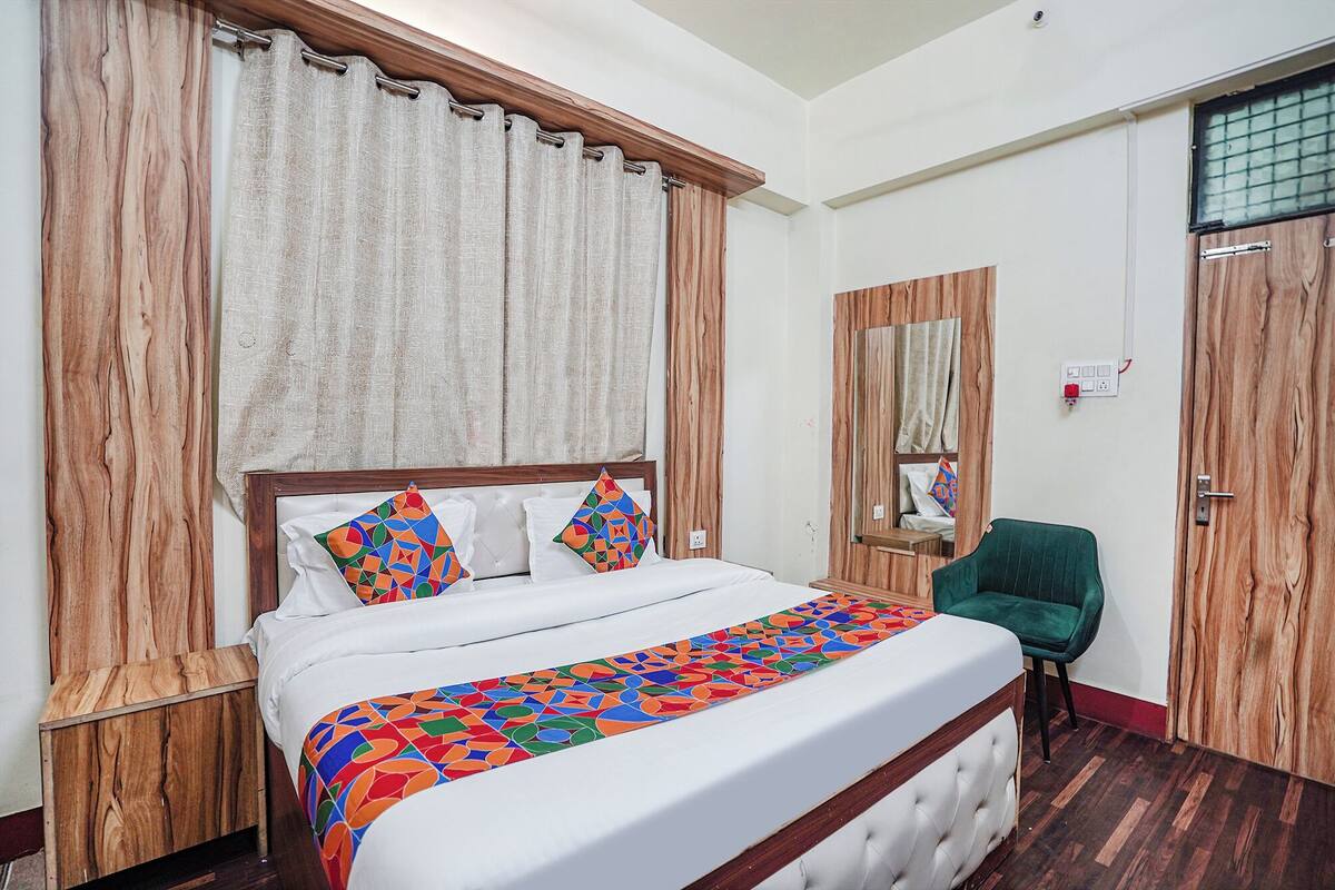 A bedroom with a large bed, wooden headboard, and a green chair.