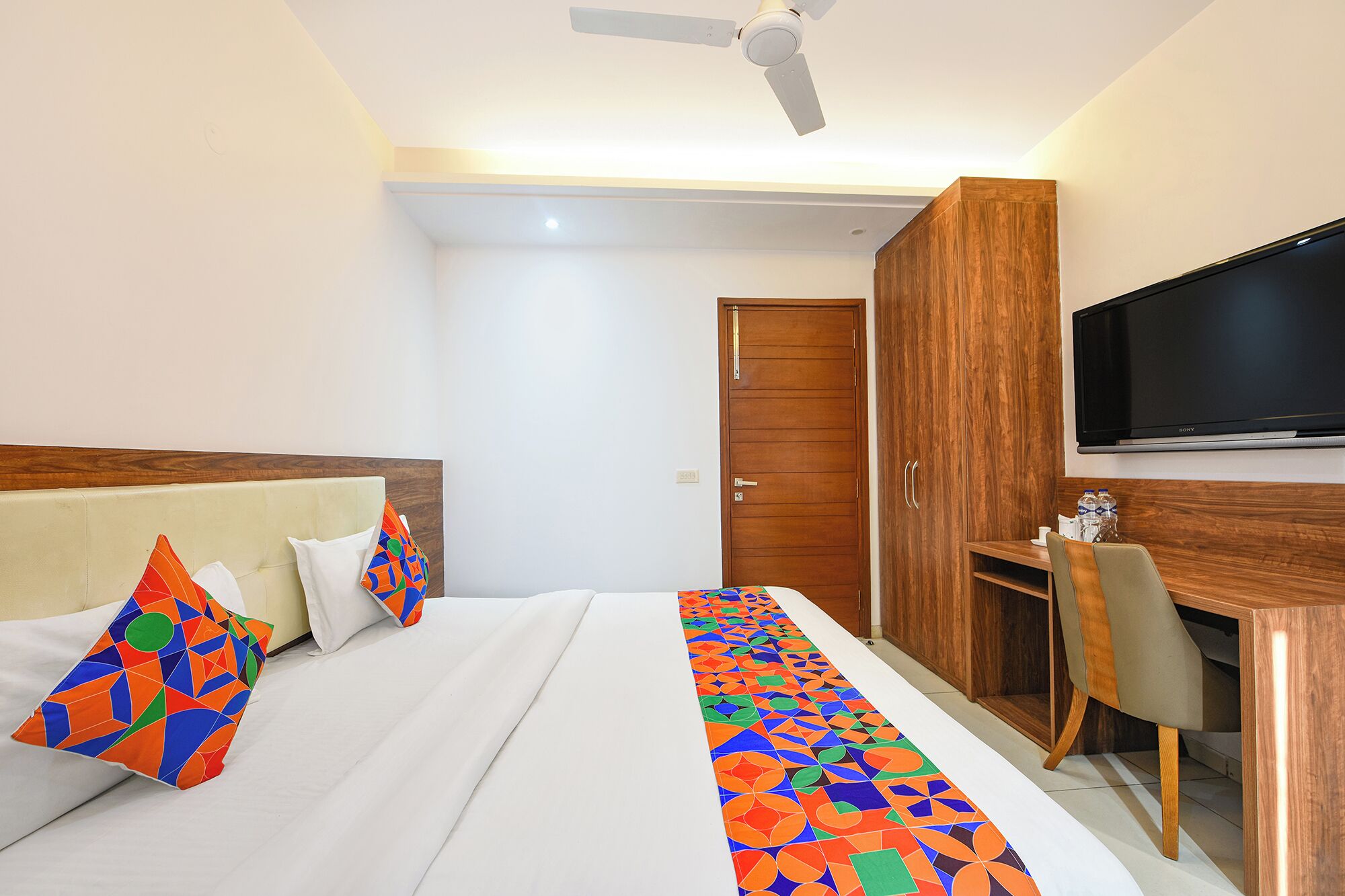 Ein Hotelzimmer mit Bett, Schreibtisch, Stuhl, Fernseher und Kleiderschrank.