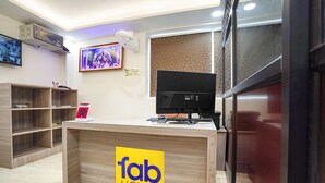 A reception desk with a 'fab hotels' sign, a television, and a digital screen displaying a video. - Fabhotel Mahalaxmii Grand (Kanpur)