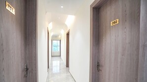 A hallway with wooden doors labeled 201 and 202, leading to a bright room with a large window. - Fabhotel Mahalaxmii Grand (Kanpur)
