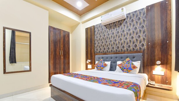 A bedroom with a large bed, wooden wardrobe, and a decorative wall panel. - Fabexpress Sr (Jaipur)