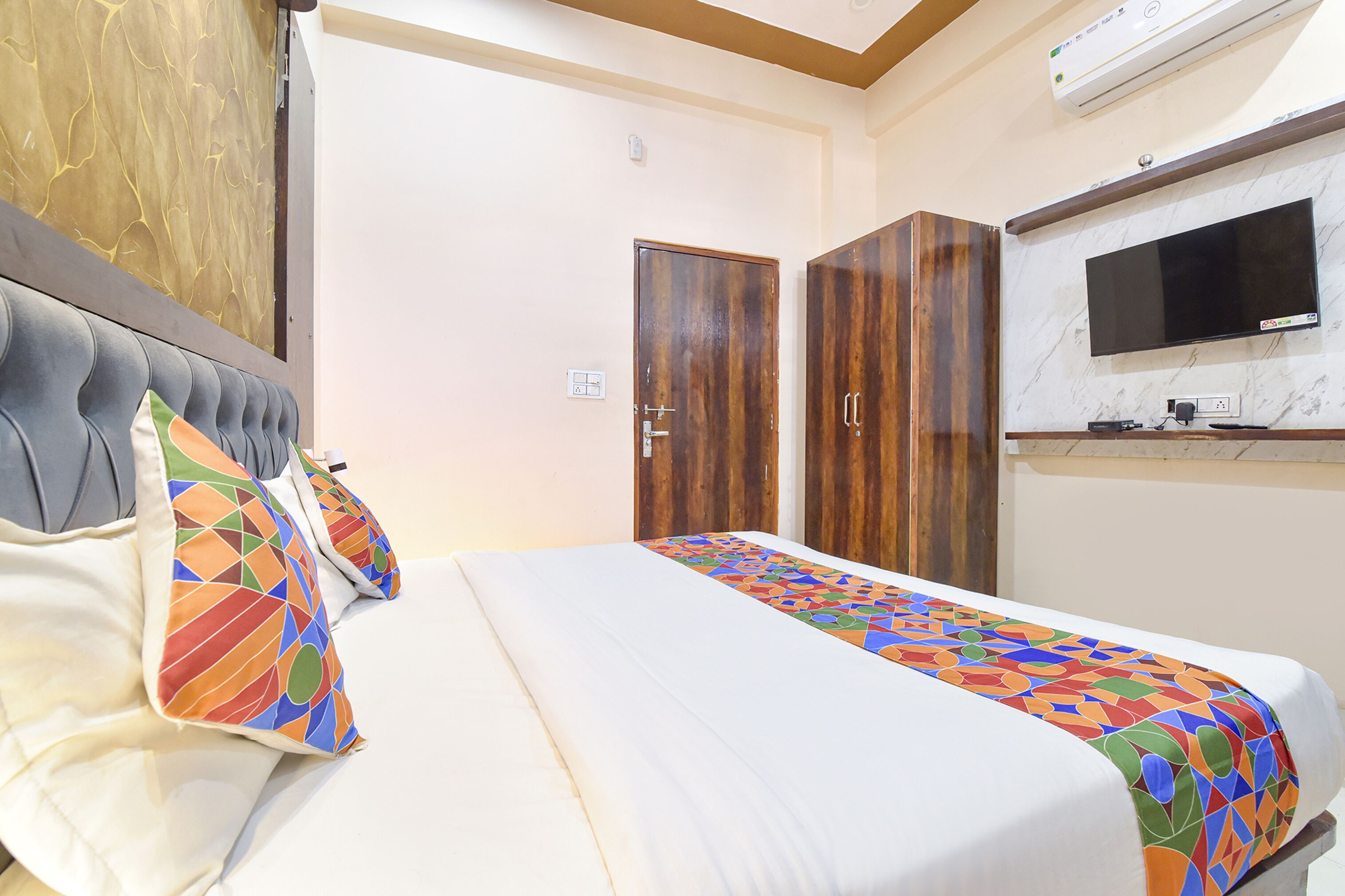 Ein Hotelzimmer mit einem Bett, einem an der Wand befestigten Fernseher und Holzschränken.
