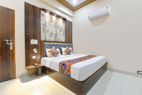 A neatly arranged bedroom with a bed, bedside table, lamp, and an air conditioning unit. - Fabexpress Sr (Jaipur)