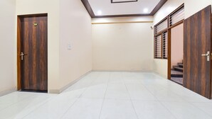 A spacious room with a wooden door labeled 204, a tiled floor, and a ceiling with recessed lighting. - Fabexpress Sr (Jaipur)