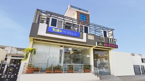 A modern hotel with a prominent 'fab hotels' sign, a balcony with potted plants, and a visible entrance. - Fabexpress Sr (Jaipur)