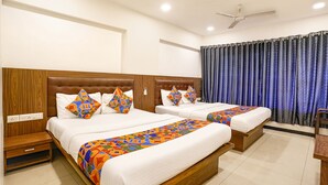 A hotel room with two beds, wooden headboards, white bedding, and a colorful geometric throw blanket. - Fabhotel Shiv Leela Grand (Mumbai)